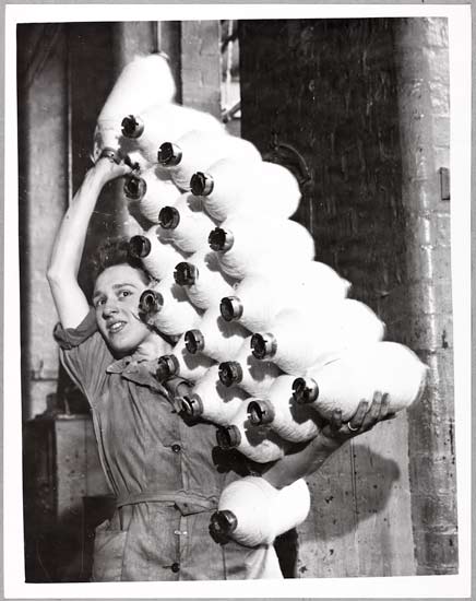 Spirit of Cotton, 1948, Bert Abell, Daily Herald Archive, ©National Media Museum Typical of the all-out effort to ensure that the industry pulls its weight in the export battle is Mrs Margaret Colley, seen carrying an outsize load of bobbins to her frame - taken at the Brook Mills, Hollingwood, Near Oldham.