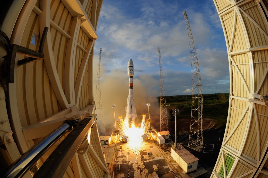 A rocket launches against the backdrop of a blue sky