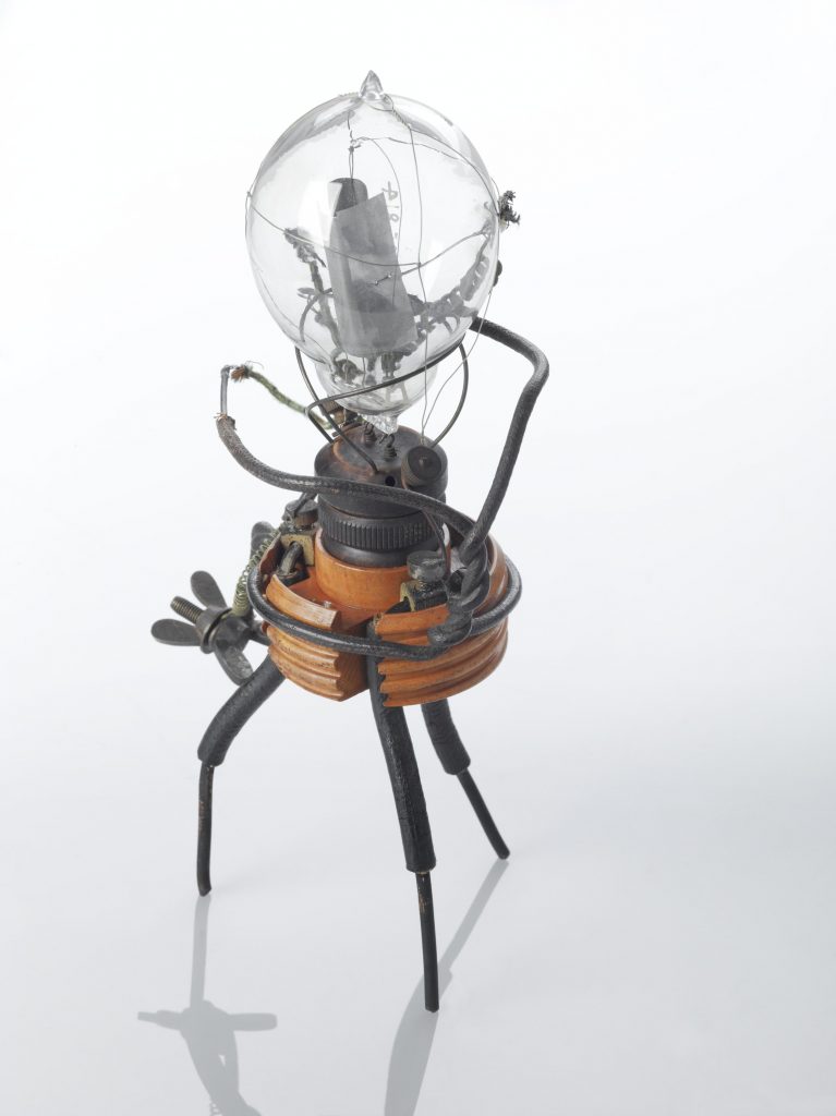 A vintage lightbulb resembling a spider with wiry legs and arms