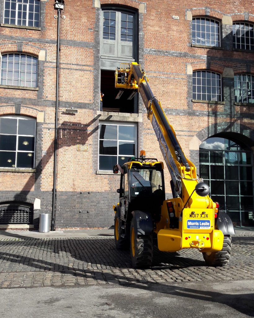 A large yellow telehandler - which looks like a tractor with an arm at the front to lift heavy crates