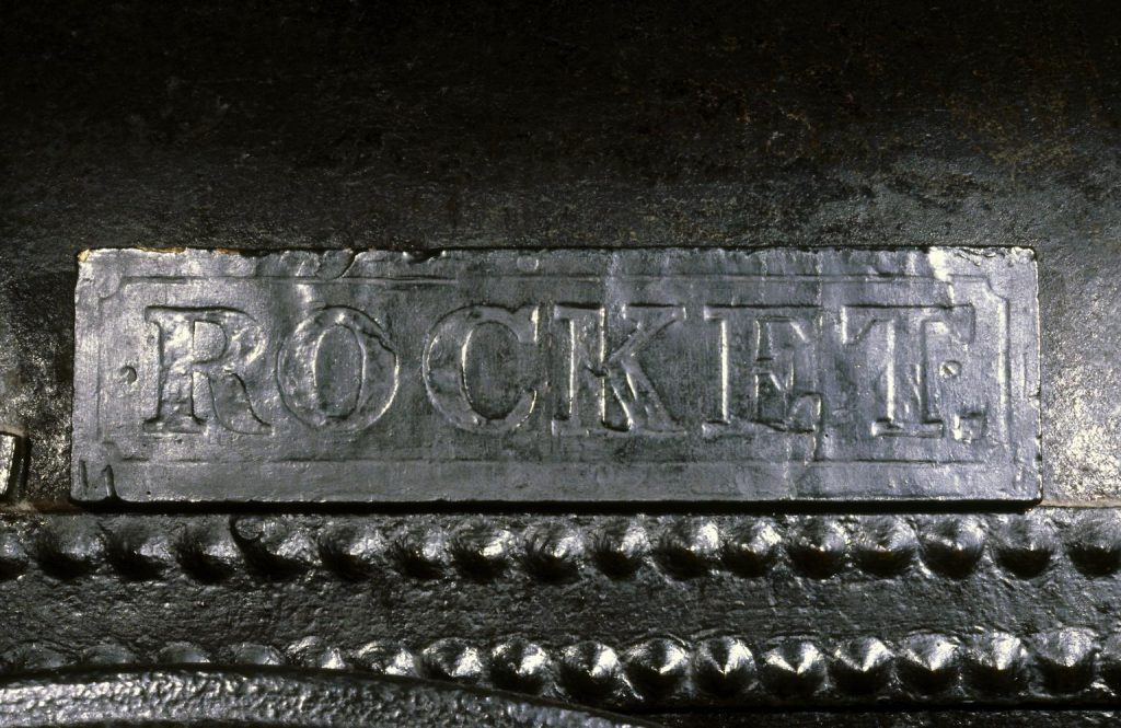 Close up of the nameplate of Stephenson's Rocket locomotive - a black plaque with "Rocket" printed in capital letters