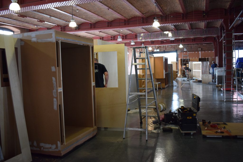 A work space during the textiles gallery refresh - ladders, toolboxes and a man building a cabinet