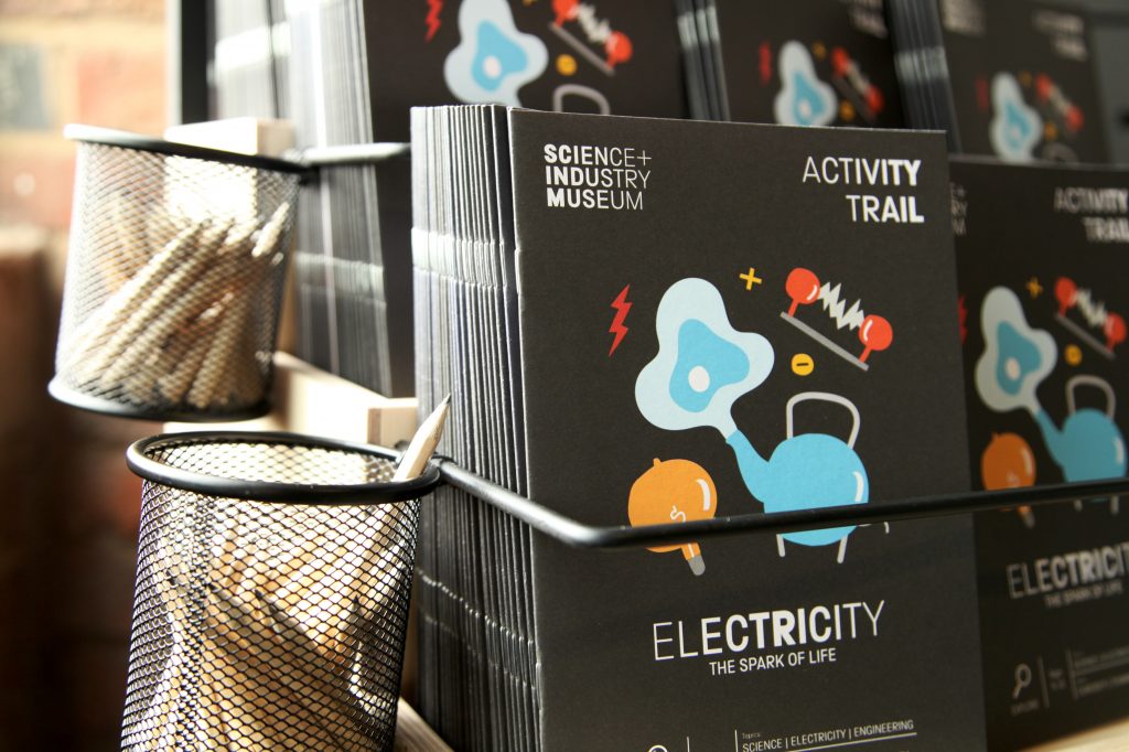 The Electricity family trail - a black brochure with a bright blue kettle and bright yellow lightbulb on the front
