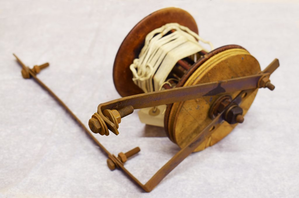 A wooden object that look slike a large fishing reel but was possibly used in the textiles industry