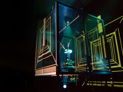 A tesla coil inside a faraday cage makes dramatically coloured sparks