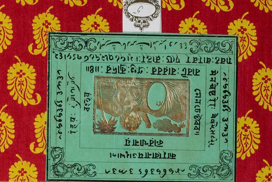 A green label with Indian writing and a gold design in the middle