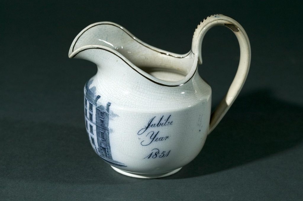 A white jug with blue detail on it
