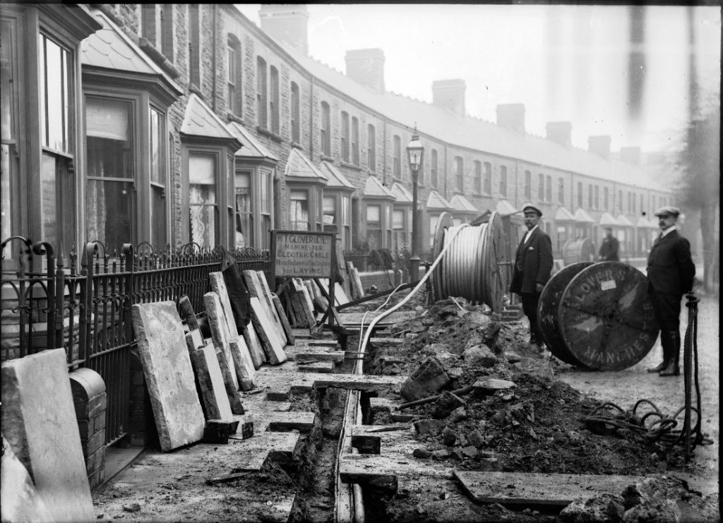 Old photo of two workmen laying electrical cable along a street