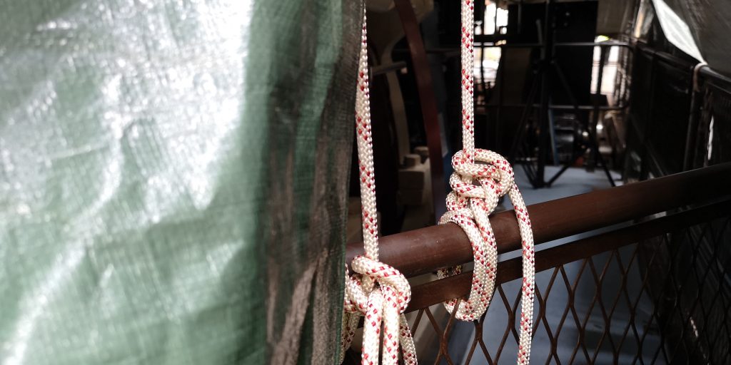 Two ropes wrapped around a brown metal barrier holding a tarpaulin down in the Science and Industry Museum's Power Hall