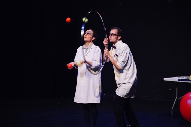 A man and a woman in white lab coats juggling