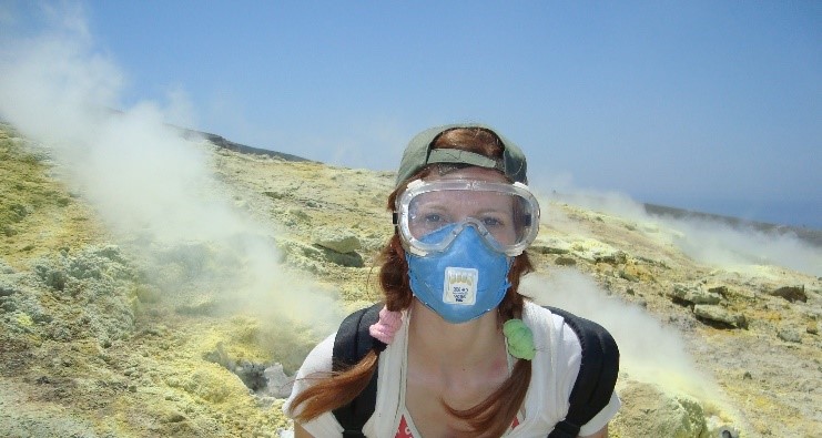 A woman stood on the side of a volcano wearing a mask