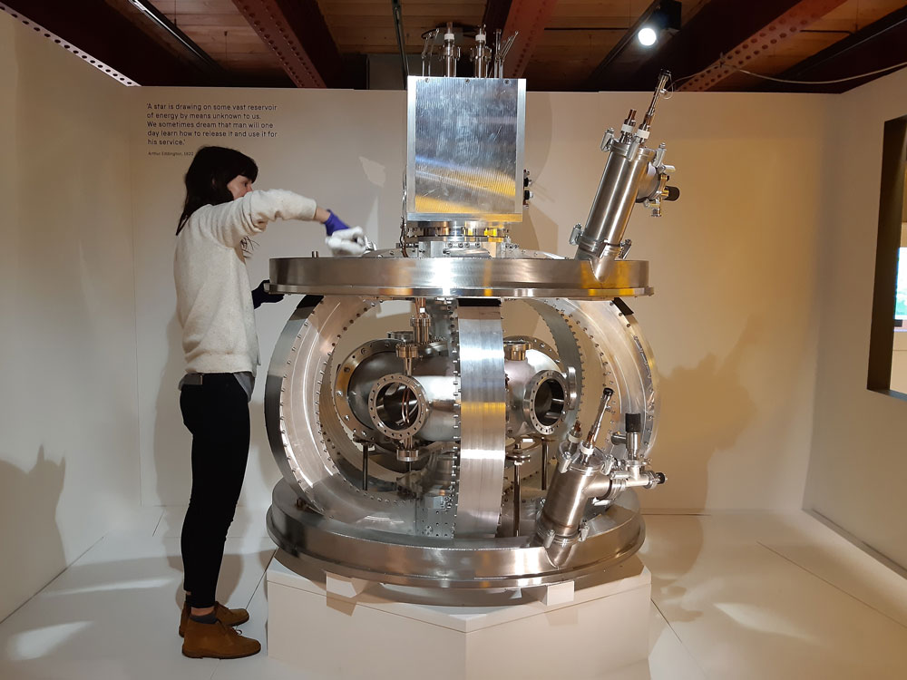 A woman cleaning a piece of machinery in a museum