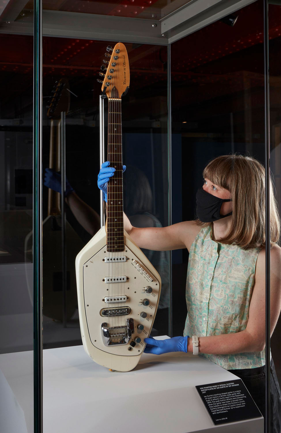 Conservator Kathryn Kreczak positioning Ian Curtis’s Vox Phantom guitar in its display case in Use Hearing Protection