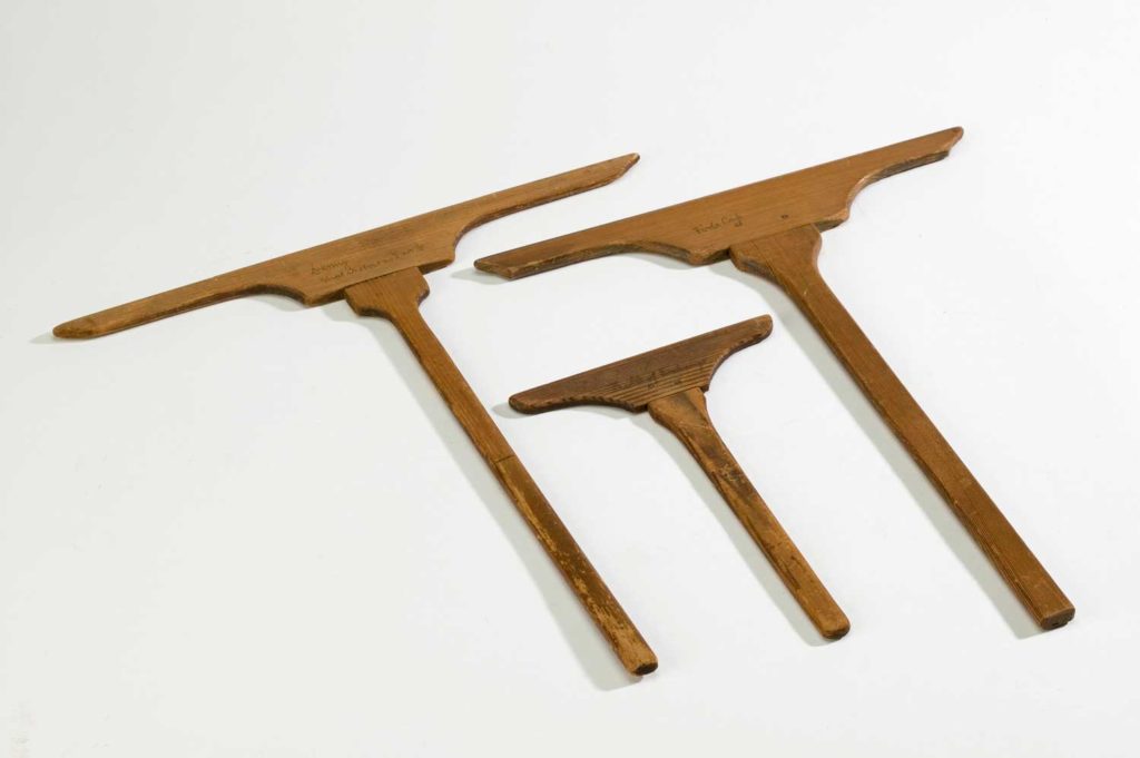 Three wooden cross-shaped tools used in the papermaking process