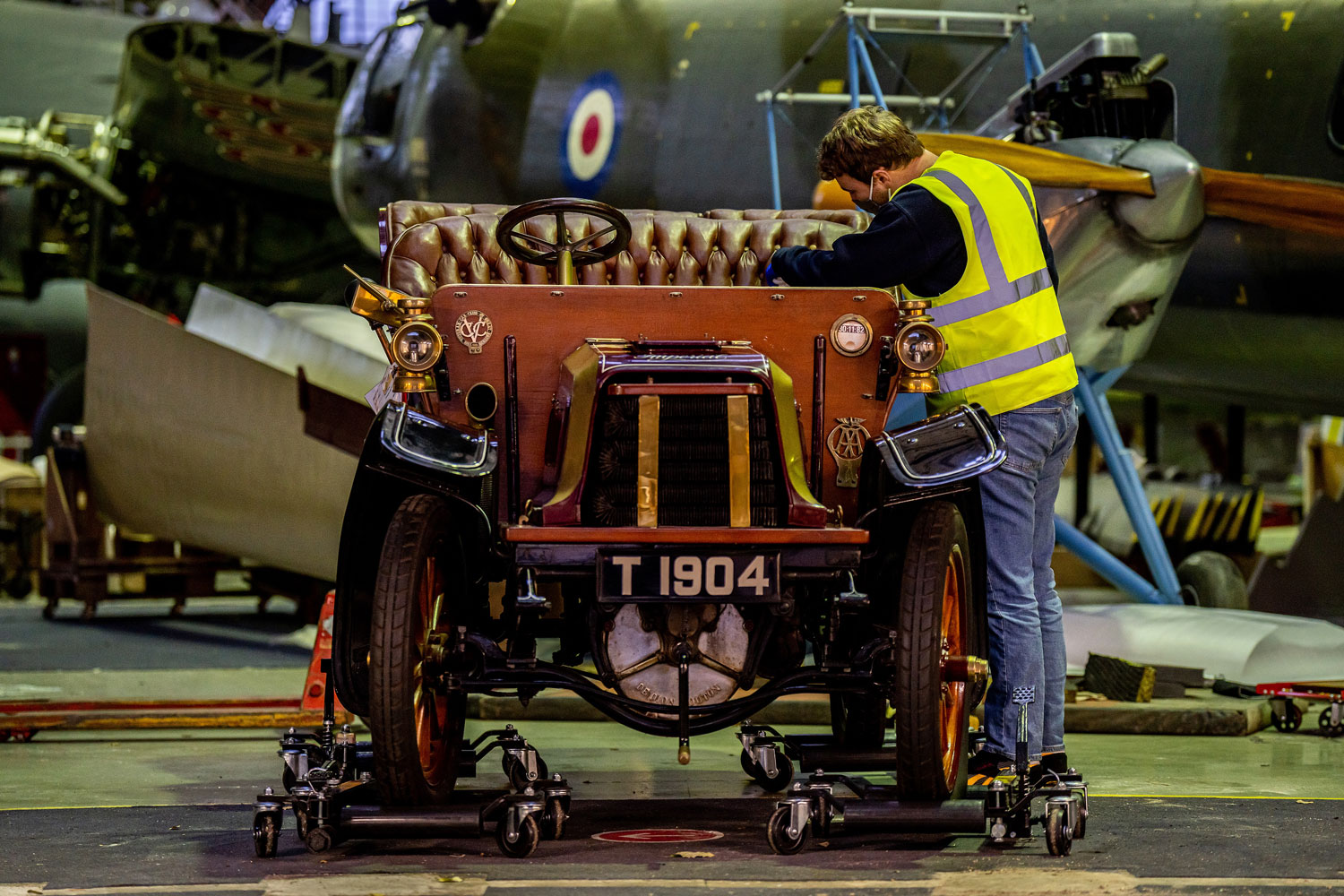 A man in a high-vis jacket cleaning the inside of an old car