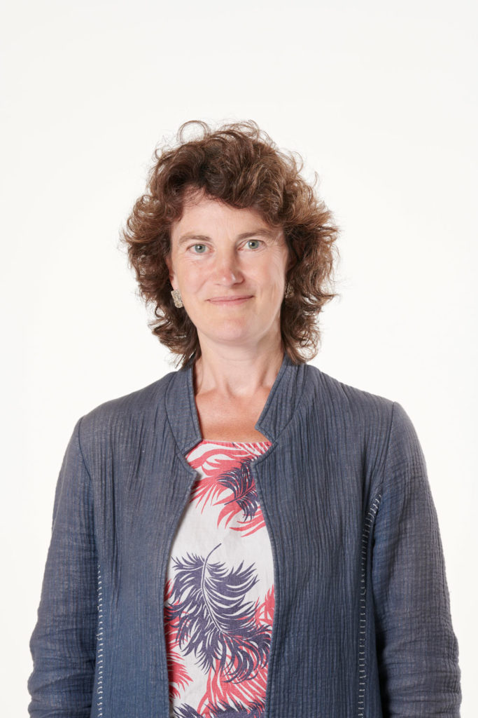 A portrait of a woman wearing a blue cardigan and red and white shirt
