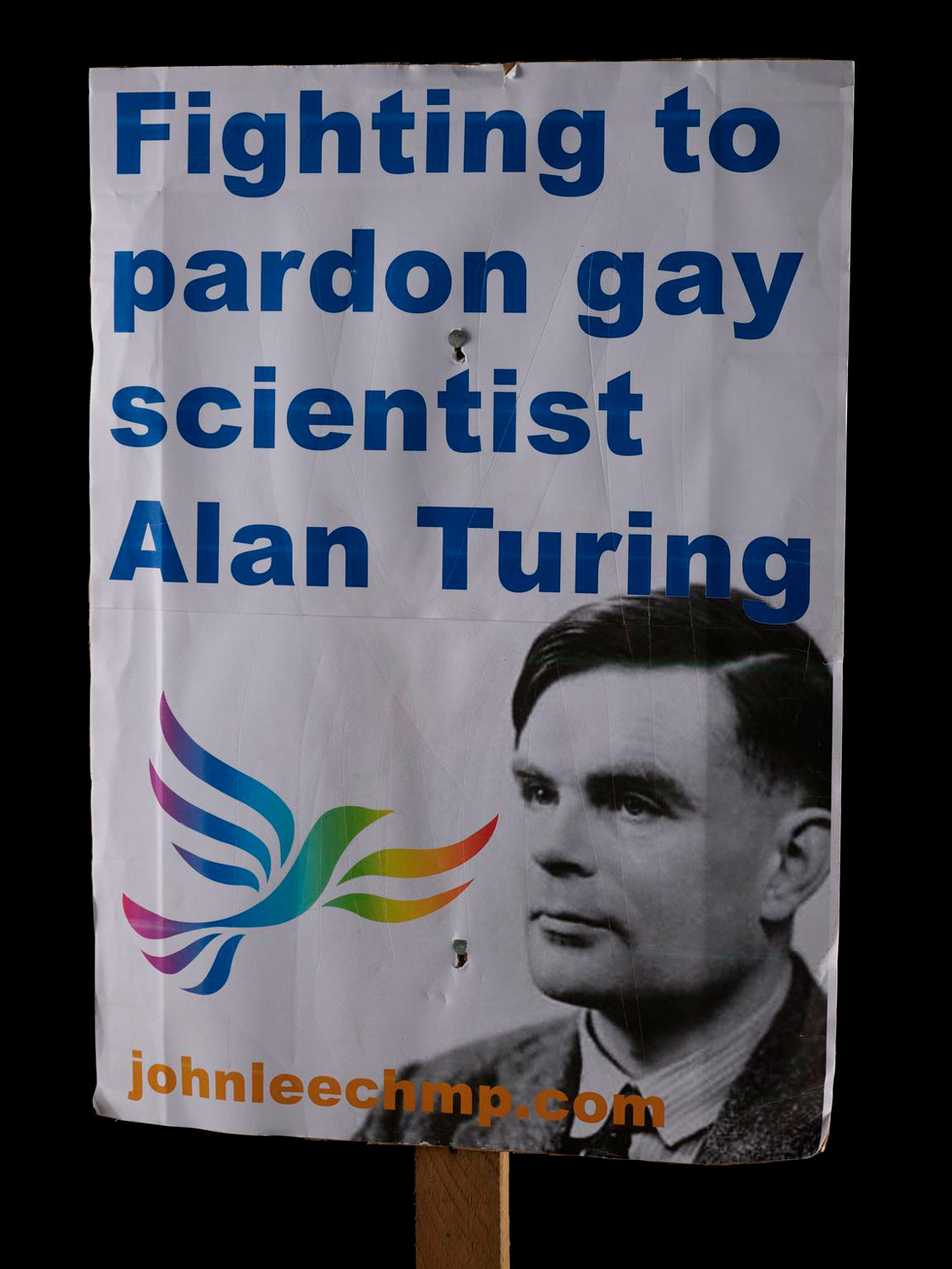 A placard with a picture of Alan Turing and a demand for his pardon written on it.