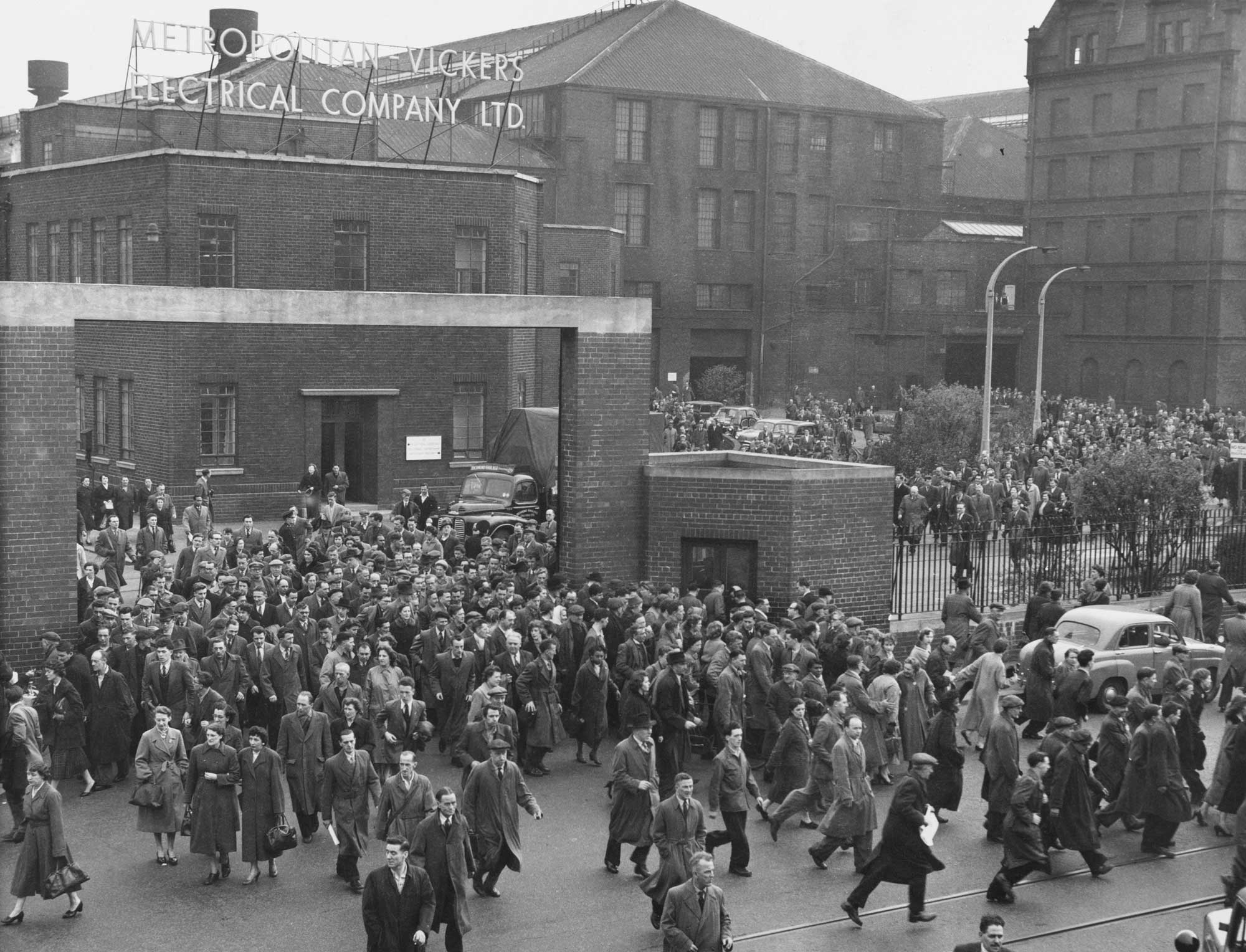 Black and white image of a large crowd of people leaving a factory