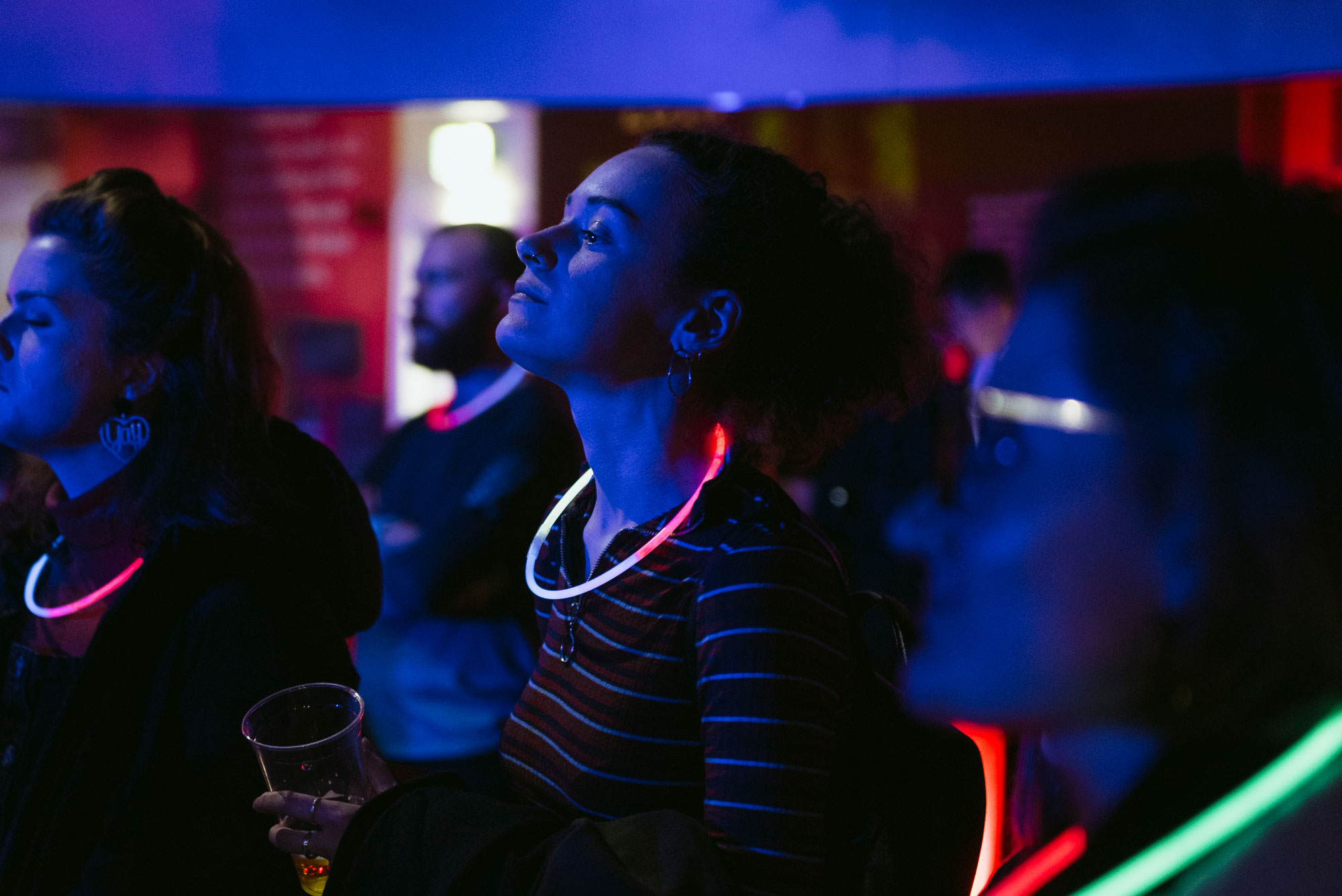 A woman in a dark room with a glow stick around her neck