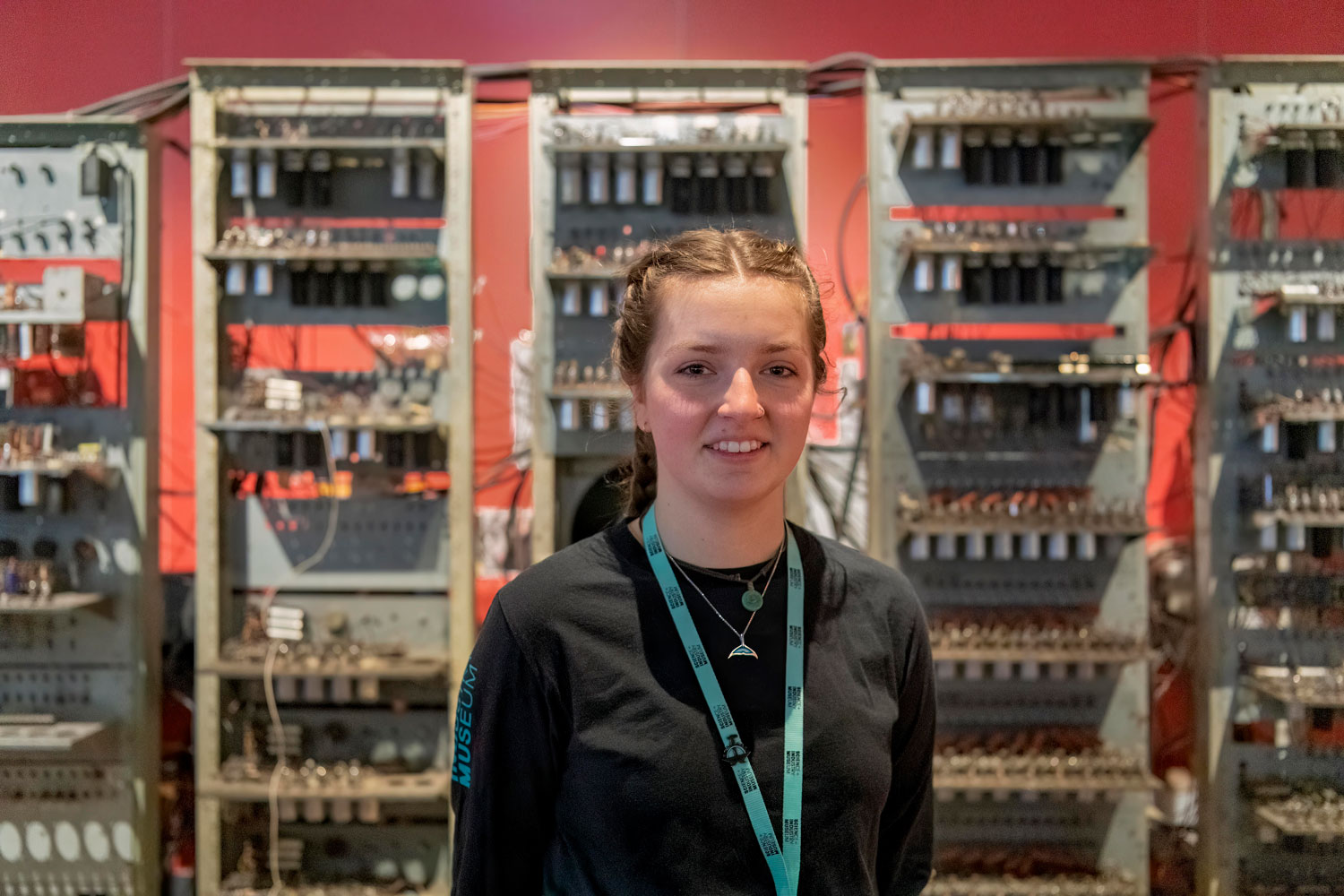 A young woman in a museum uniform stood in front of an early computer.
