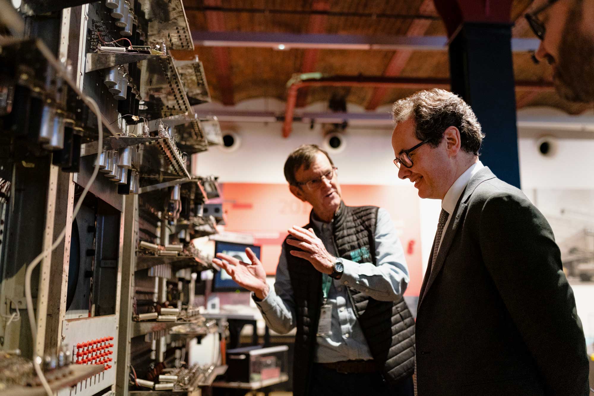 Two men looking at an early computer on display in a museum