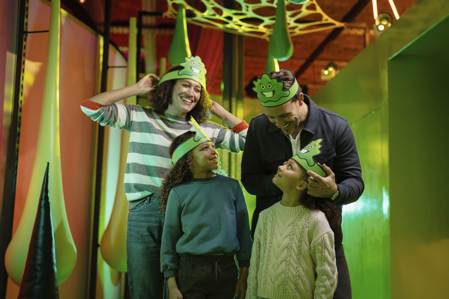 A family inside the Operation Ouch exhibition, all wearing hats shaped like 'bogies'