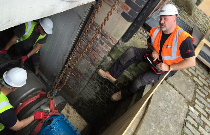 Image of maintenance workers moving an engine from a basement.