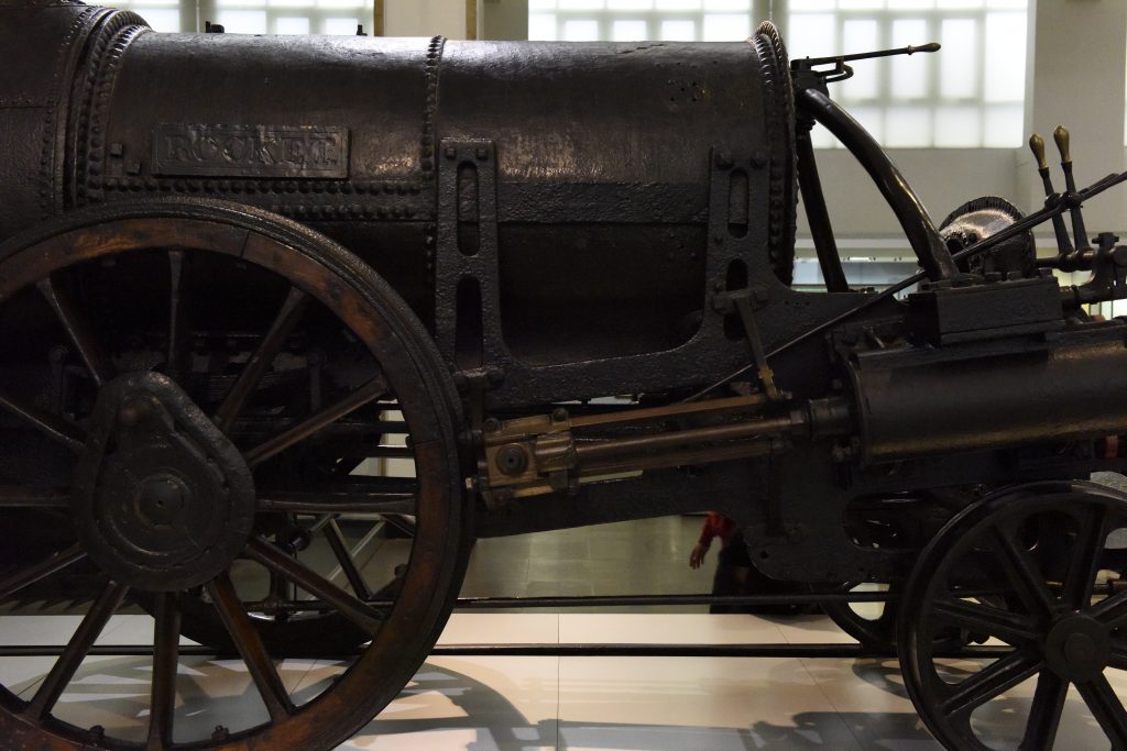 Close up of the back part of the Rocket locomotive showing the wheels, gears and levers made out of a dark coloured metal