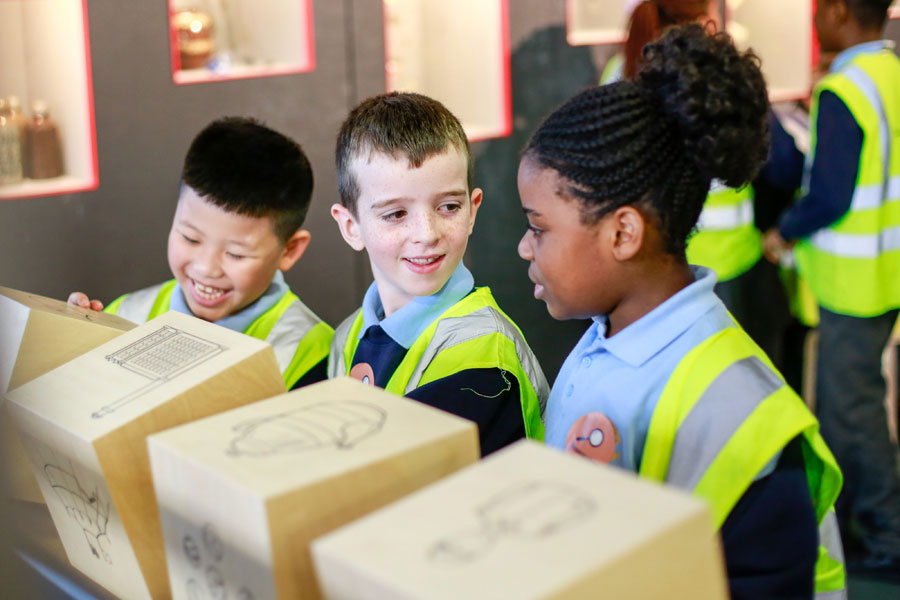 Three children wearing high-vis jackets in a museum gallery