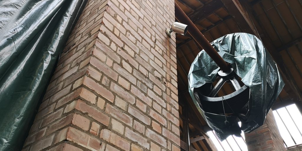 A machine wheel in the rafters of the Science and Industry Museum's Power Hall has been mostly covered by a green tarpaulin