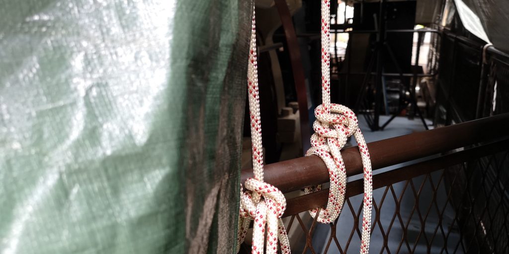 Two ropes wrapped around a brown metal barrier holding a tarpaulin down in the Science and Industry Museum's Power Hall