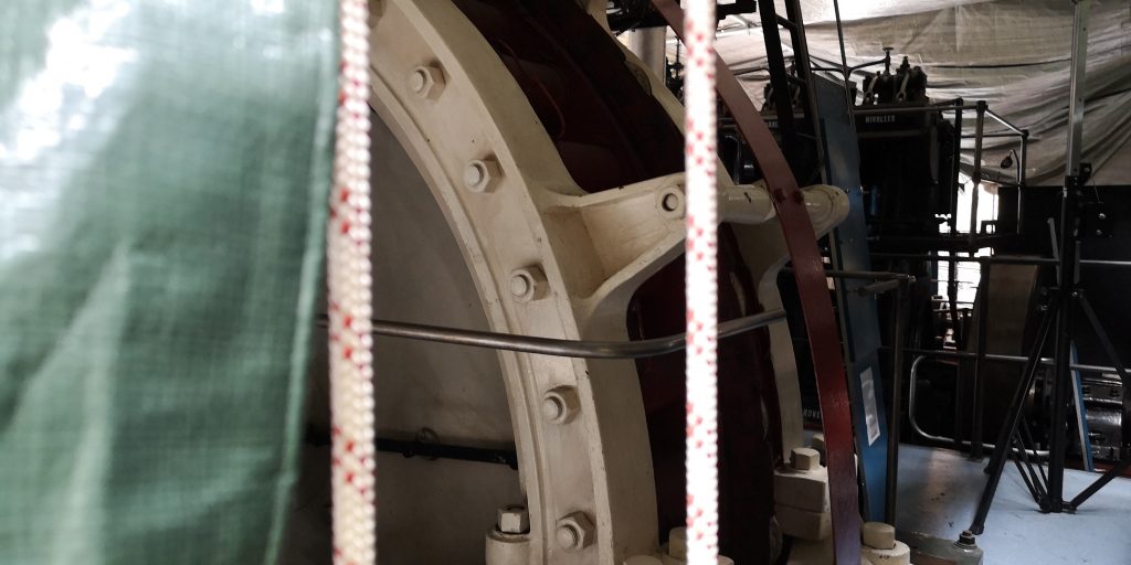 A white-coloured machine is partially covered by tarpaulin in the Science and Industry Museum's Power Ha;;