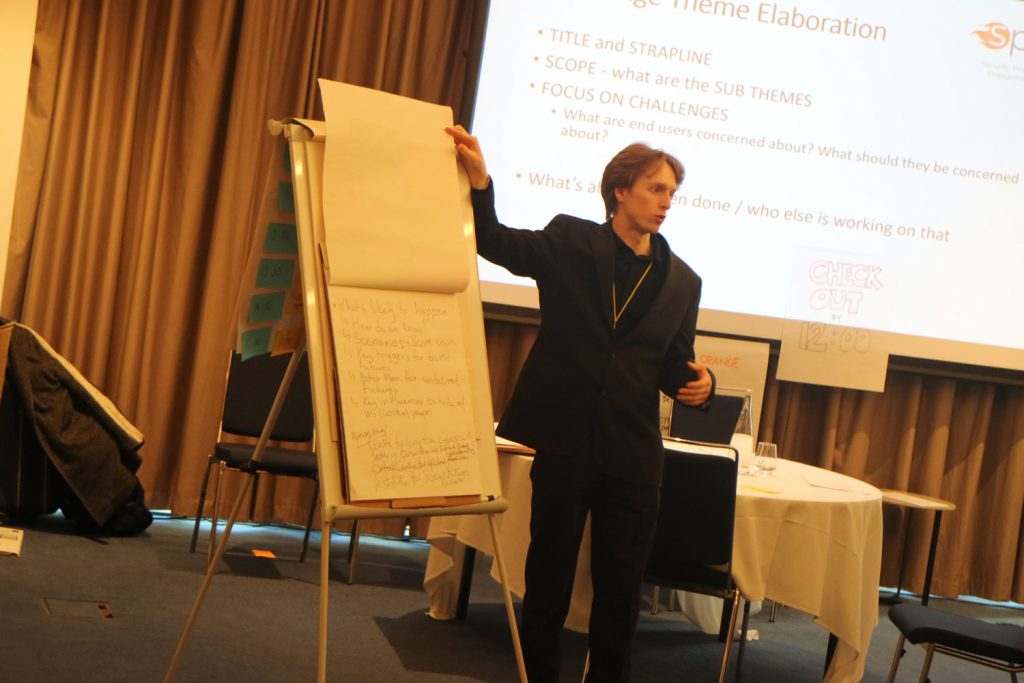 a man stood in front of a flip chart giving a presentation