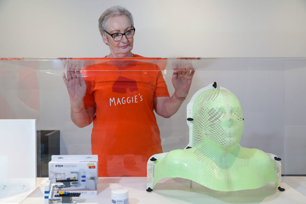 A woman in an orange t-shirt looking at medical equipment in a glass cabinet