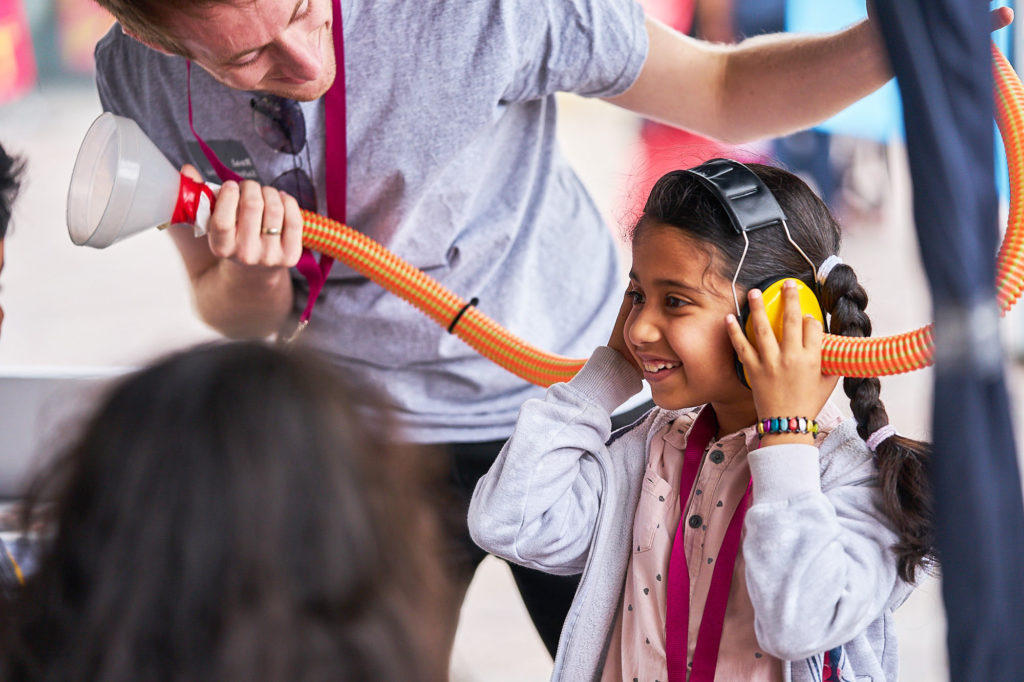 A young girl holding two tubes to her ears