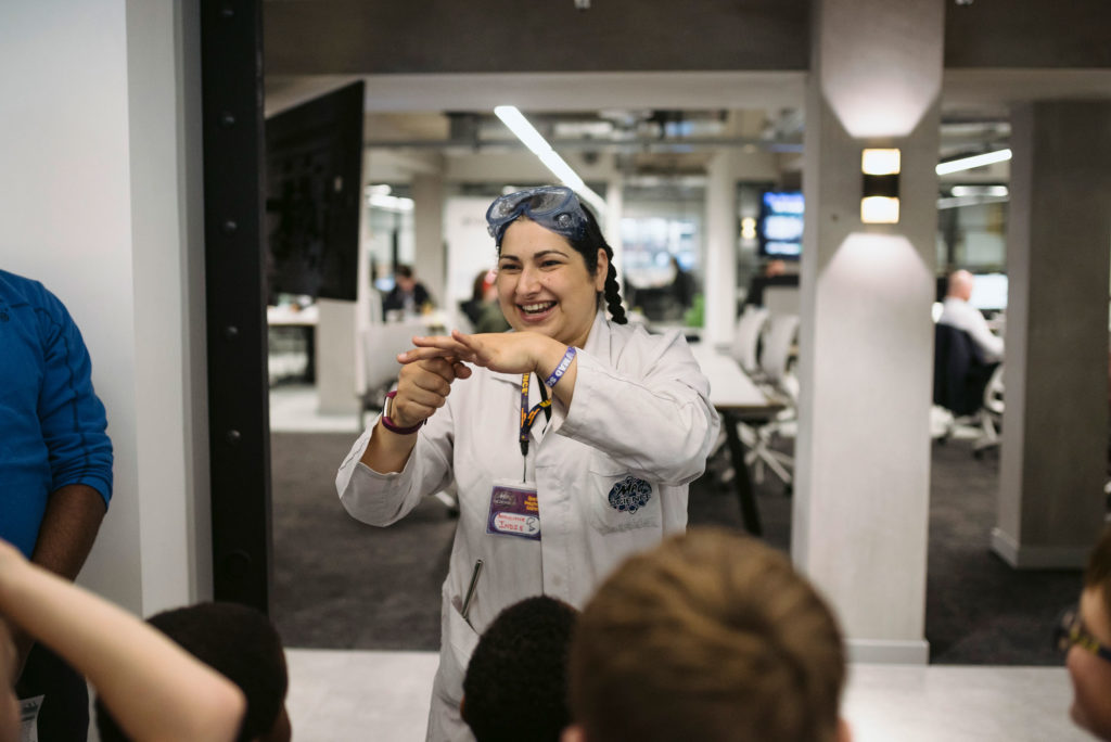 A woman in a lab coat presenting to people in front of her