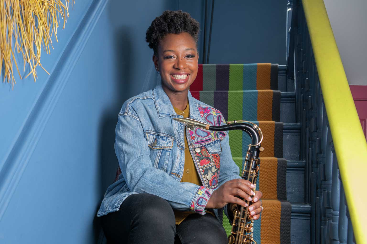 A woman sat on a staircase holding a saxophone