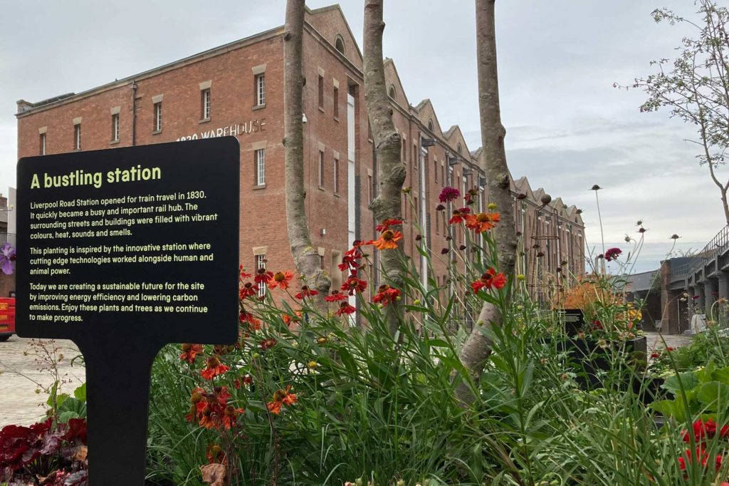 A flower bed in front of an old warehouse