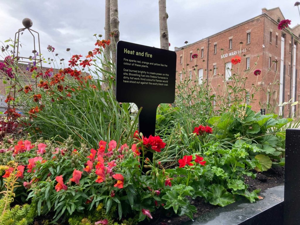 A flower bed in front of an old warehouse