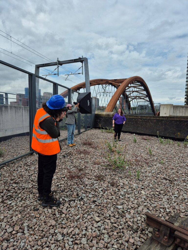 A woman posing for a photo next to a railway bridge