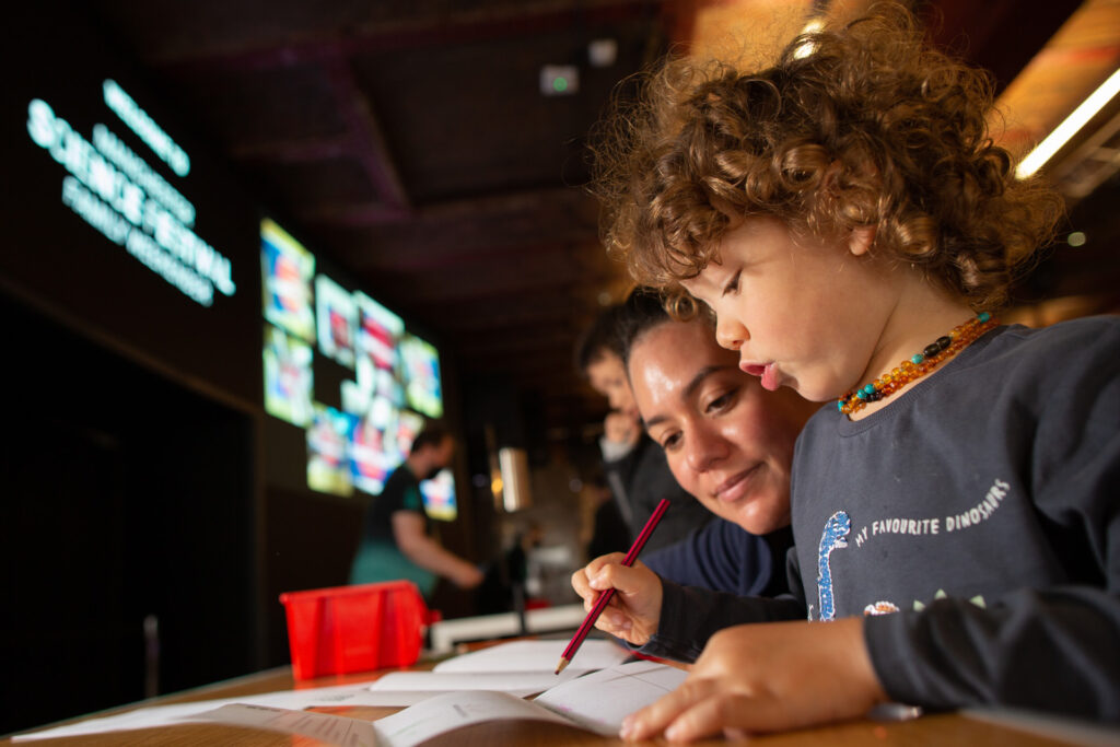A woman and a child drawing together at a museum