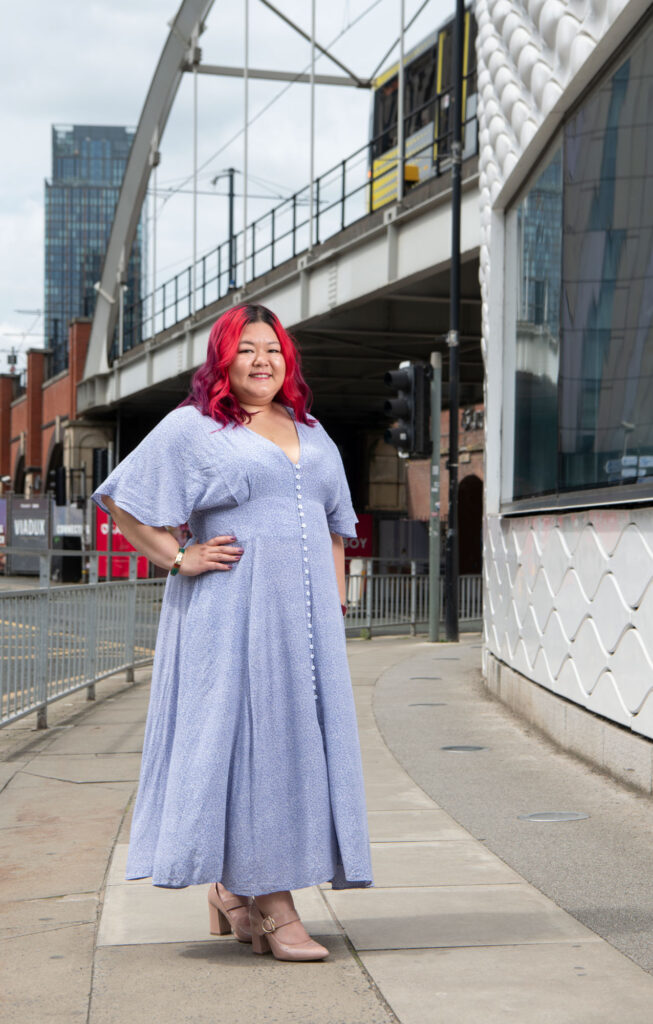 A woman posing for a photo in front of a railway bridge