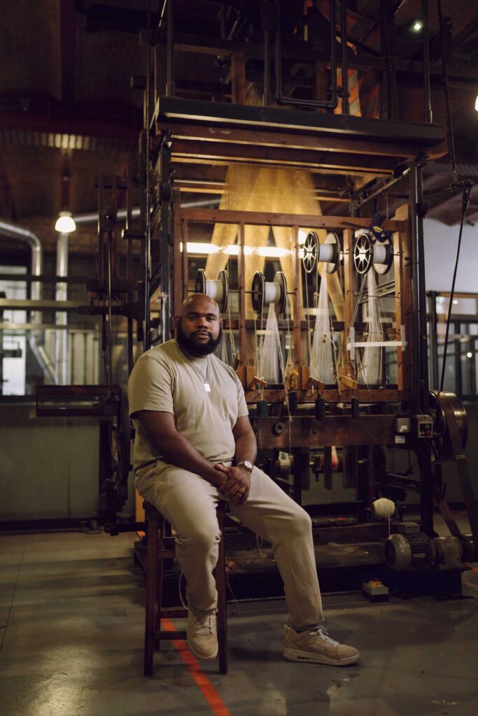 A man sat on old textiles machinery, on display in a museum